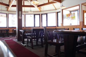 a dining room with tables and chairs and windows at Snow Freak Sunrise in Zao Onsen