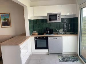 a small kitchen with white cabinets and a microwave at Ans'O - Les Anses d'Arlet in Les Anses-dʼArlets +11 photos