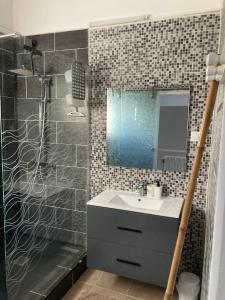 a bathroom with a sink and a shower with a mirror at Ans'O - Les Anses d'Arlet in Les Anses-dʼArlets