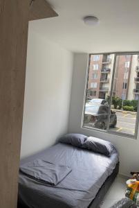 Un dormitorio pequeño con una cama y una ventana. en Apartamento Nuevo con Piscina Bien Ubicado, en Villavicencio