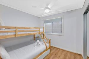 a bedroom with two bunk beds and a window at Sandy Cove Apartment The Entrance 8 in The Entrance +5 photos