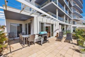 a patio with a table and chairs in front of a building at Sandy Cove Apartment The Entrance 8 in The Entrance
