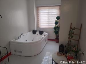 a large white bath tub in a room with a window at Serenity Homes with Indoor Jacuzzi in Lipa