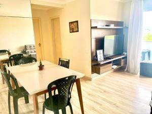 een eetkamer met een tafel, stoelen en een televisie bij Apt Ilhéus próximo a Praia dos Milionários in Ilhéus