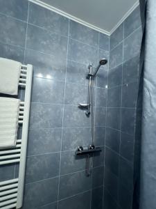 a shower in a bathroom with blue tiles at Apart Canada Center in Baia Mare