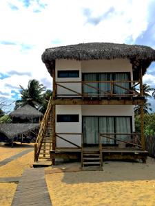 a building with a straw roof on a beach at Na Praia Pousada in Barra Grande