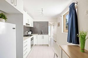 a kitchen with white cabinets and a blue curtain at Rustic Queen Room in Glebe - Next to USYD - Shared Bathroom in Sydney