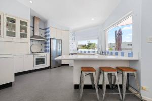 a kitchen with white cabinets and a counter with stools at Norah Head Beachside living with Private rooftop in Norah Head