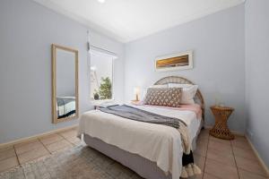 a white bedroom with a bed and a mirror at Norah Head Beachside living with Private rooftop in Norah Head