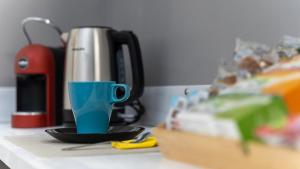 a blue cup sitting on a counter next to a coffee maker at Elephant and Castle - Exclusive Holiday Home in Catania