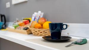 a blue coffee cup sitting on a counter with a basket of fruit at Elephant and Castle - Exclusive Holiday Home in Catania