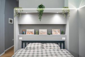 a bedroom with a bed with plaid sheets and plants at Elephant and Castle - Exclusive Holiday Home in Catania