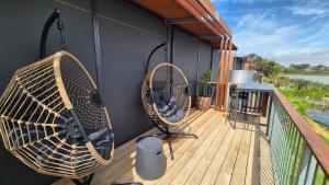 a balcony with two wicker chairs and a fan at Lake Wellington Luxury Retreat in Wellington East +29 photos