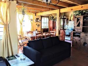 a living room with a black couch and a kitchen at CASA FAMILIAS muy cerca PLAYA Y Av3 in Villa Gesell +15 photos