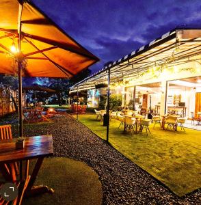 a patio with tables and chairs and umbrellas at night at Casa Hotel Bremen in Circasia