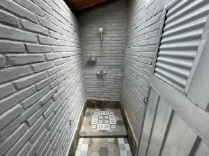 a bathroom with a shower with a brick wall at Saka Homestay Boutique & Cafe in Borobudur