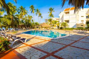 una piscina con sedie e palme presso il resort di OCEANPARADISE to you ALBATRO l Y ll a Juan Dolio