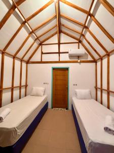 two beds in a room with a door at MAI LAKU Cottage in Sekotong