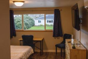 a bedroom with a bed and a desk and a window at Private Home - Playground, Jumping Mat, BBQ, Darts, Firepit, Gazebo, 4 Smart TVs, White Cotton Bedding, - The Redwood Cul-De Sac Beach Retreat in Crescent City
