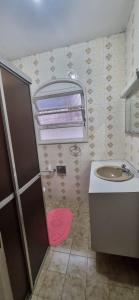 a bathroom with a sink and a toilet and a mirror at Casa na praia das Astúrias in Guarujá