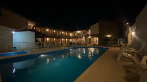 a swimming pool at night with chairs around it at Hosteria Torol Calta in Villa Cura Brochero