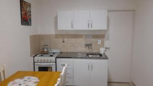 a kitchen with white cabinets and a sink and a table at Soñar en la Patagonia in Trelew