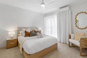 a white bedroom with a large bed and a chair at Stylish 3-Bed Apartment in Coastal Redcliffe in Redcliffe