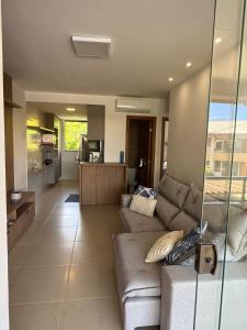 a living room with a couch and a kitchen at Luxo Novo - 250m Praia - Nascente - 2 Suítes - Beachtênis, Tênis, Campo in Itacimirim