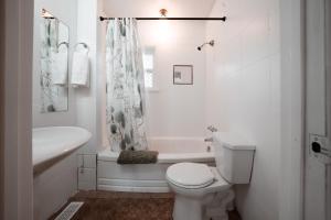 a white bathroom with a toilet and a tub and a sink at Stay & Play - Central Family Friendly in Calgary +30 photos