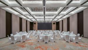 a room with tables and white chairs and a screen at Holiday Inn Liaoyuan City Center by IHG in Liaoyuan