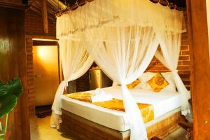 迪克韦勒Lunuvila Resort Hiriketiya Dikwella的卧室里有一张带白色窗帘的四柱床