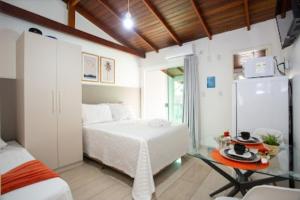 a bedroom with a bed and a table and a refrigerator at Pousada Doce Encanto in Florianópolis