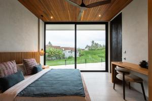 a bedroom with a bed and a desk and a window at Villa Famara Pererenan, Canggu by Blacksand in Tumbak Bayuh +40 photos
