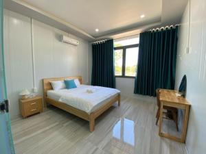a bedroom with a bed and a desk and a window at Dalis Waterfall Homestay in Lagi