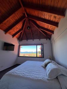 a bedroom with a large bed with a large window at Depto Vista Soñada en Bariloche in Dina Huapi