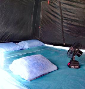 - un lit dans une tente avec un ventilateur et un oreiller dans l'établissement Mai Rut Beach Eco Camping, à Ban Nong Wiwat