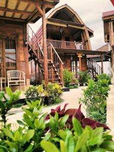 a large wooden house with a porch and some plants at Melasti Mountain Villas Amed in Amed
