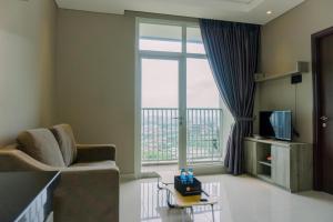 a living room with a couch and a large window at Modern Look 1BR at 22nd Floor Ciputra International Apartment By Travelio in Jakarta
