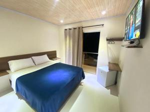 a bedroom with a blue bed and a flat screen tv at Hotel Junior in Caazapá