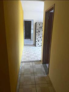 an empty hallway with yellow walls and a tile floor at Confort Casa in São João de Meriti