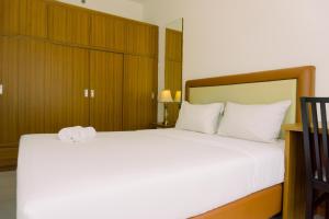 a bedroom with a large bed with white sheets at Warm and Minimalist 1BR Apartment at Scientia Residence By Travelio in Tangerang +15 photos