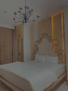 ein Schlafzimmer mit einem großen weißen Bett mit einem Kronleuchter in der Unterkunft Villa Grand Baiti in Jarakan