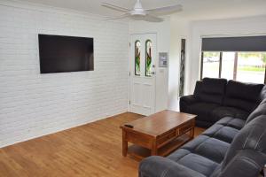 a living room with a couch and a tv at Sutts Retreat - Bring your own linen. in South West Rocks