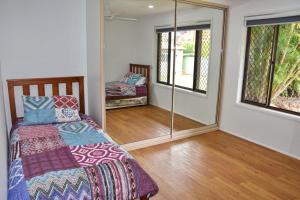 a bedroom with a bed and a mirror at Sutts Retreat - Bring your own linen. in South West Rocks