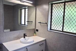 a bathroom with a sink and a mirror at Sutts Retreat - Bring your own linen. in South West Rocks +12 photos