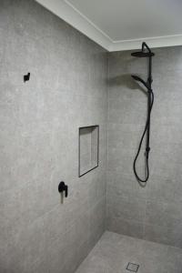a bathroom with a shower with a shower head at Sutts Retreat - Bring your own linen. in South West Rocks