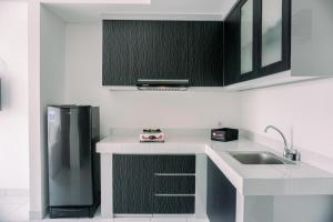 a kitchen with a sink and a refrigerator at Wonderful 1BR Casa De Parco Apartment near ICE BSD By Travelio in Tangerang