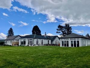 a large white house with a cross on top of a field at 74 on Lockhart in Oturehua