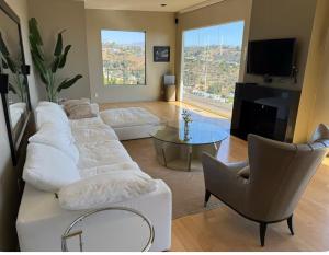 a living room with white furniture and a large window at Secluded Luxury Hollywood Hills Retreat in Los Angeles
