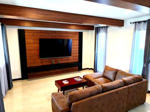 a living room with a couch and a flat screen tv at Baan Suan Sawan Villa in Krabi